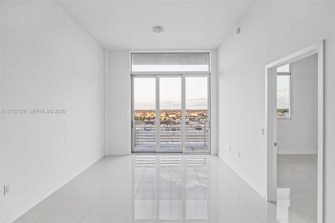 Interior space featuring 24x24 tile flooring, floor-to-ceiling glass sliding doors, and a private balcony with horizontal metal railings