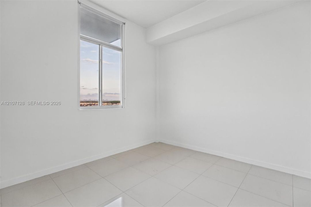 Bedroom featuring high ceilings, light-colored tile flooring, and blackout window treatment