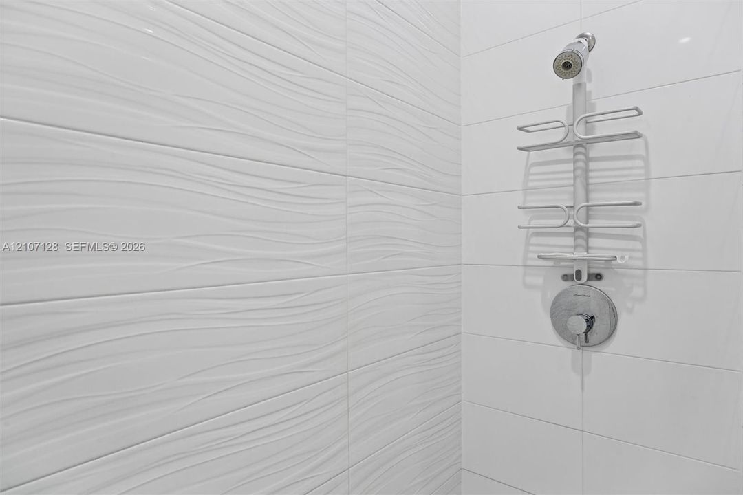 Textured white wall tiles with a wave-pattern finish, complemented by smooth white rectangular tiles.