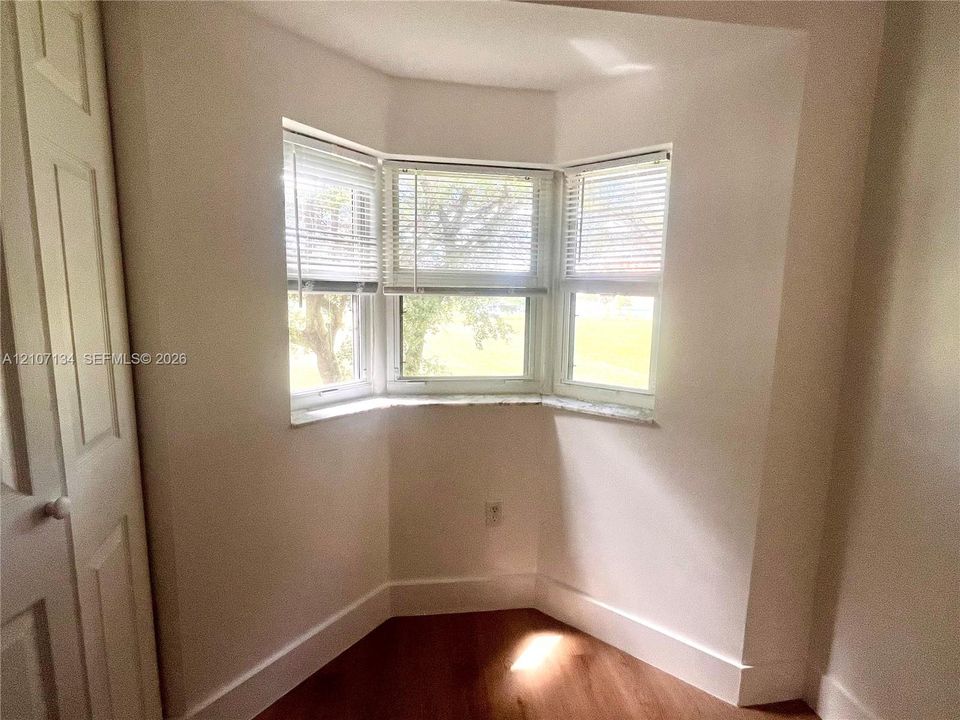 Bay window featuring tripartite casement windows with stone-finish sills, wood-finish flooring, and built-in closet with multi-panel door