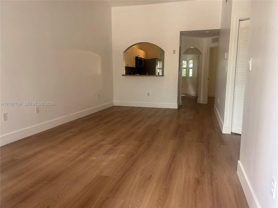 Interior space featuring wood-finish flooring, an arched wall cutout, and a louvered-panel door