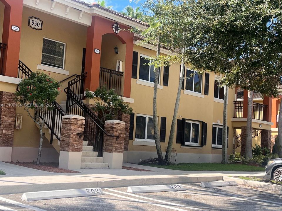 Two-story exterior featuring stucco siding, stone masonry accents, decorative shutters, and metal railing stairs