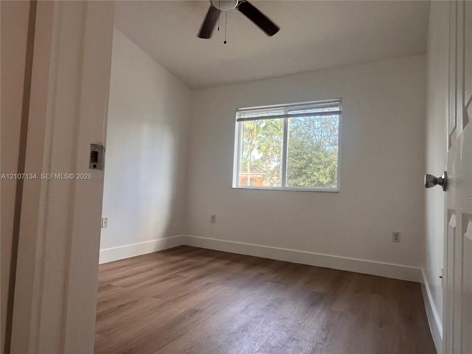 Interior space featuring wood-finish flooring, a neutral color palette, a central ceiling fan, and a dual-pane window