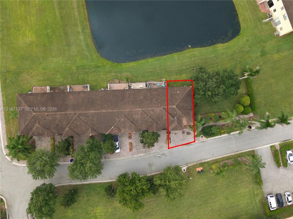 Aerial perspective highlighting a multi-unit property with a shingle roof, paver driveway, and mature landscaping