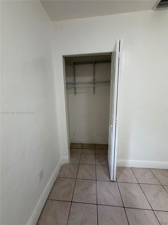 Closet featuring white paneled door and metal wire shelving, complemented by tile flooring