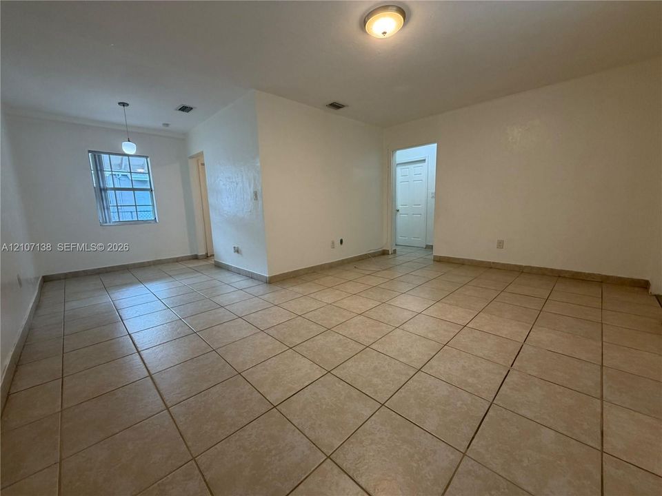 Interior space featuring neutral wall paint, large-format tile flooring, a hanging pendant light, and a flush-mount ceiling fixture