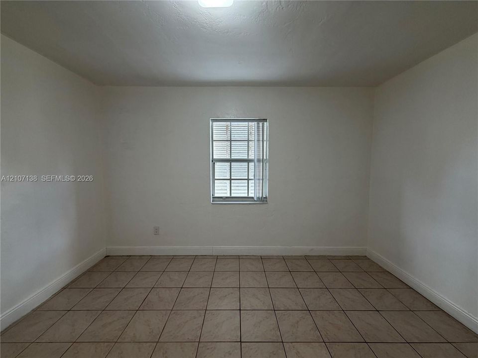 Neutral-toned square tile flooring, smooth wall finishes, and a single-pane grid-pattern window