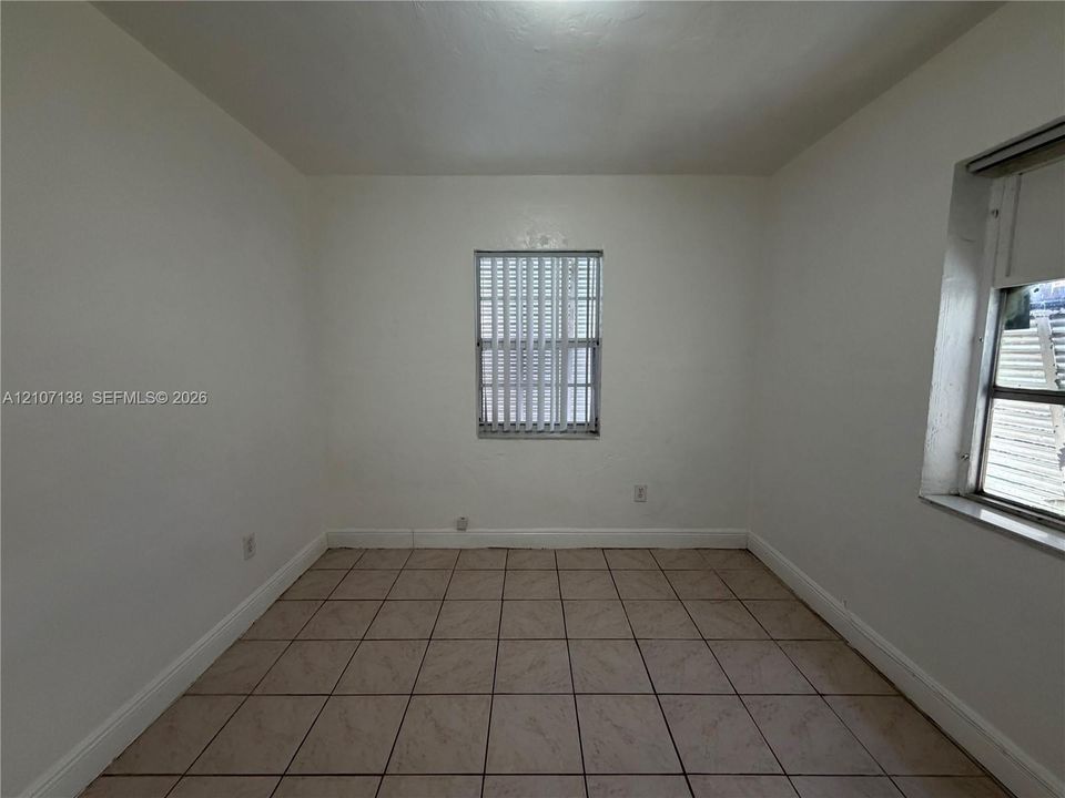 Interior room featuring neutral wall finishes, tile flooring, and dual window openings