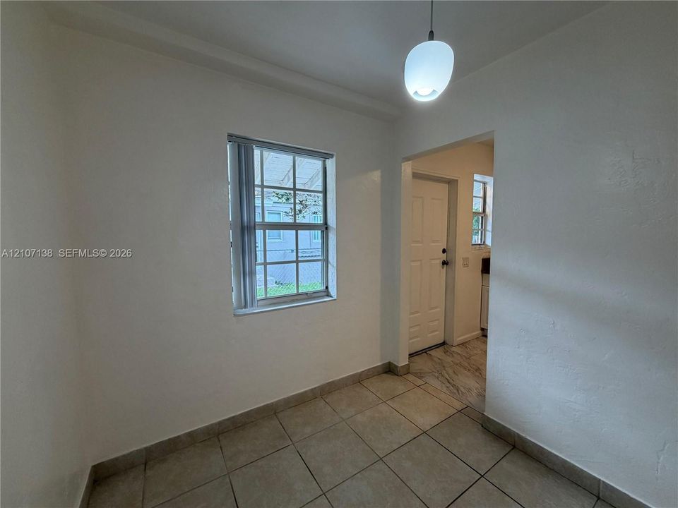 Interior space featuring neutral wall tones, ceramic tile flooring, a multi-pane window, and a single pendant light fixture