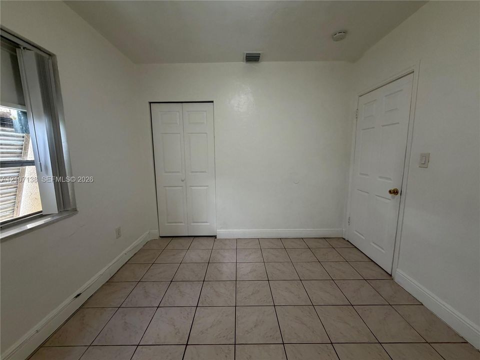 Neutral-toned tile flooring, two-panel interior doors, and a double-panel closet door