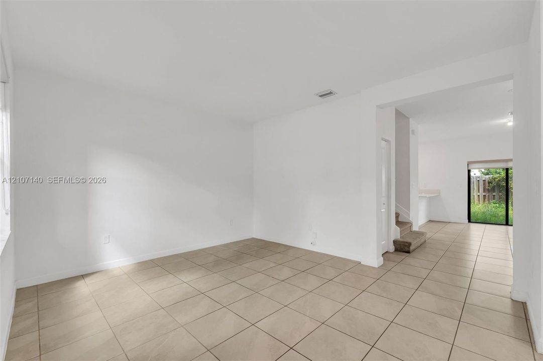Neutral-toned tile flooring, white wall finishes, and glass sliding door providing exterior access