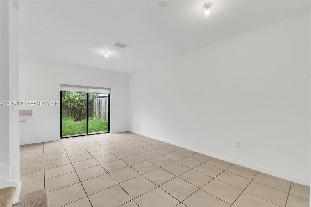 Neutral-toned ceramic tile flooring, expansive wall space, and sliding glass doors providing outdoor access