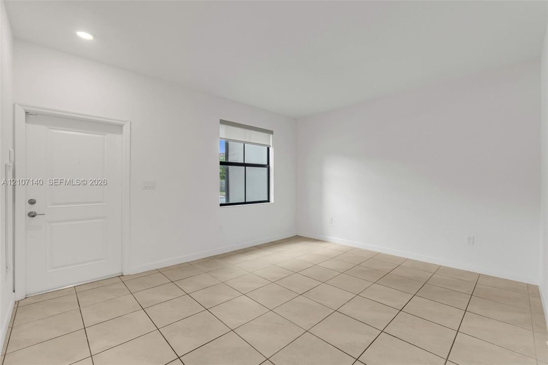 Neutral-toned ceramic tile flooring, recessed ceiling lighting, and a single-panel interior door