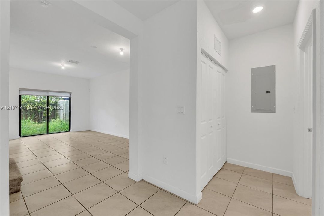 Neutral-toned ceramic tile flooring, sliding glass door, white bifold closet doors, and recessed lighting