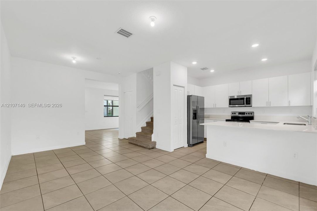 Kitchen featuring white cabinetry, solid-surface countertops, and stainless steel appliances, complemented by tile flooring and recessed lighting