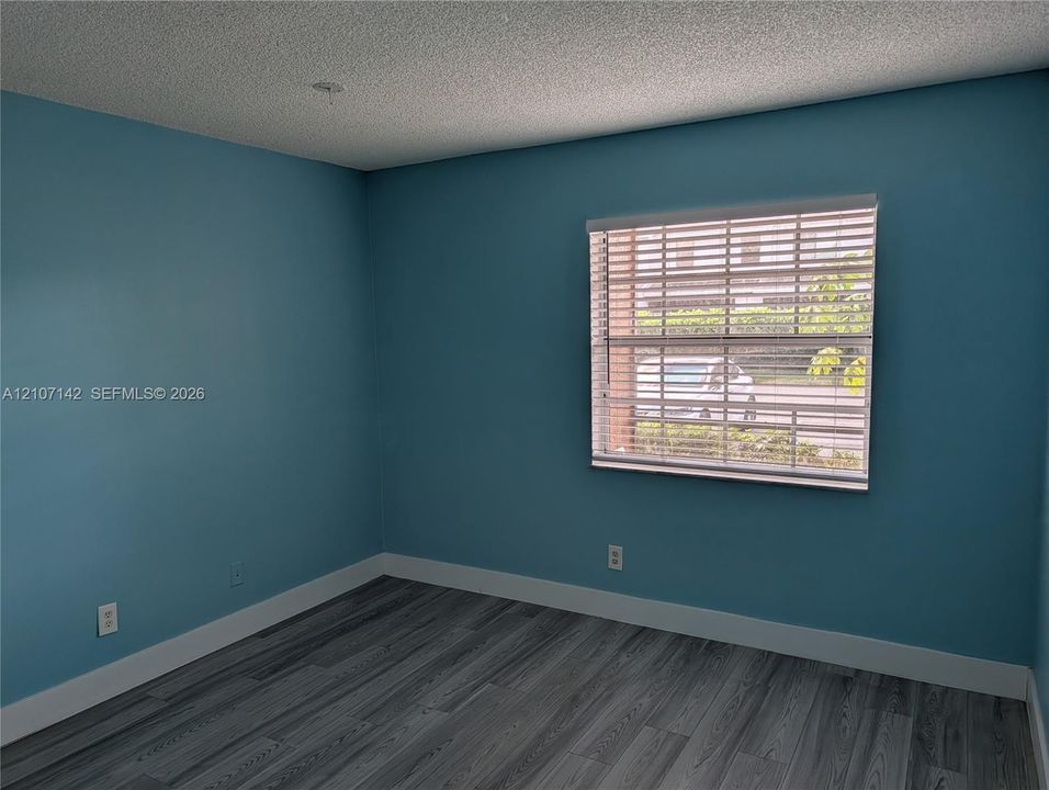 Room featuring wood-finish flooring and a window with horizontal blinds
