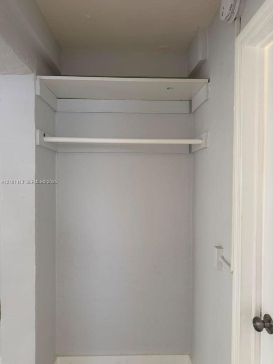 Storage closet featuring a built-in shelf and hanging rod
