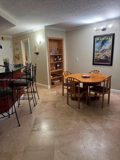 Neutral tile flooring, built-in recessed shelving with wood trim, and a breakfast bar with stone-surfaced countertop