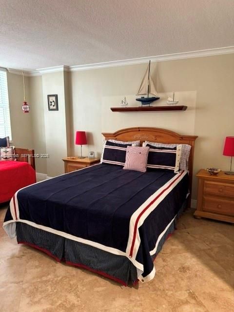 Stone flooring, neutral wall tones, crown molding, and a custom built-in wood shelf