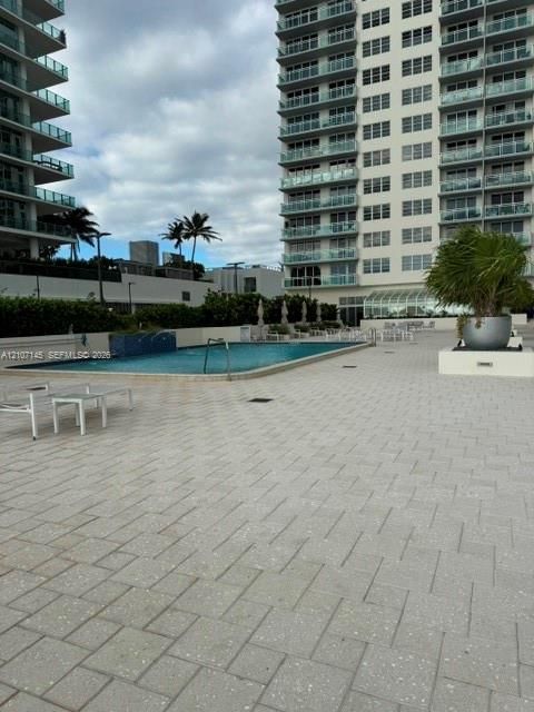 Outdoor pool deck featuring a tiled hardscape, mosaic-accented water feature, and integrated landscape planters