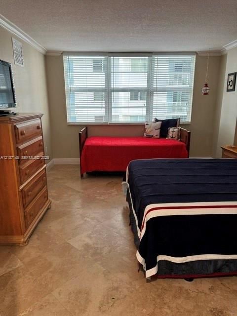 Large room featuring neutral wall tones, crown molding, and polished stone tile flooring with a triple-pane window configuration