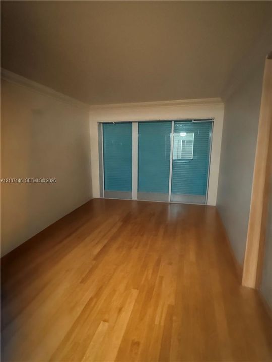 Interior space featuring wood-finish flooring, neutral wall tones, and triple-panel sliding glass doors