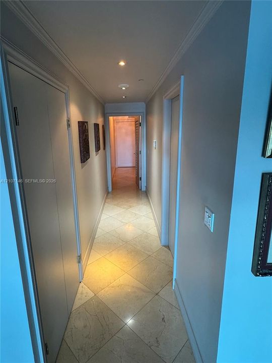 Hallway featuring stone tile flooring laid in a diamond pattern, recessed ceiling lighting, and crown molding