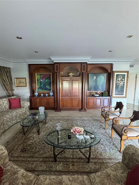 Custom built-in wood cabinetry with arched niches, recessed ceiling lighting, and crown molding