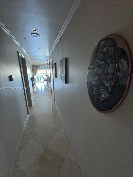 Hallway featuring polished stone tile flooring, crown molding, and recessed lighting