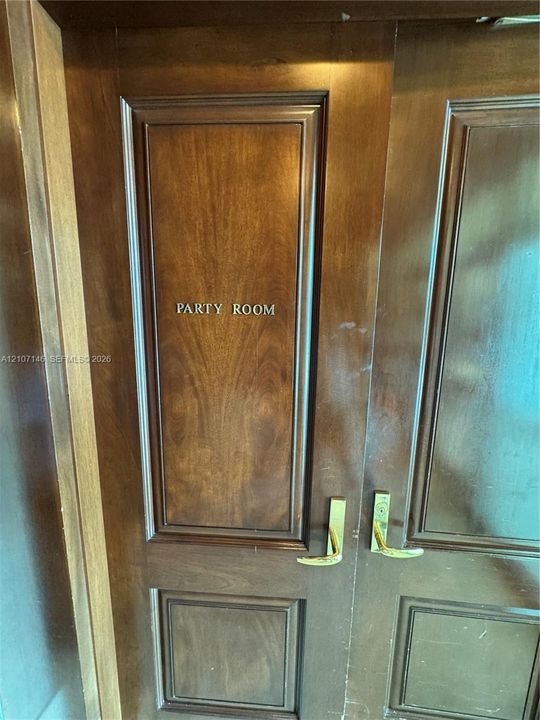 Double-leaf solid wood doors featuring recessed panel detailing, custom metal signage, and polished brass lever-style hardware