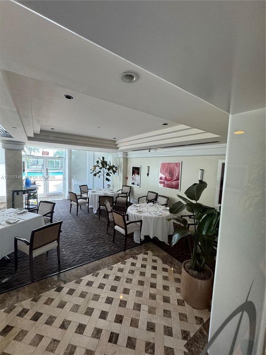 Grand interior featuring a tiered tray ceiling, recessed lighting, stone-patterned tile flooring, and wall-mounted sconce lighting