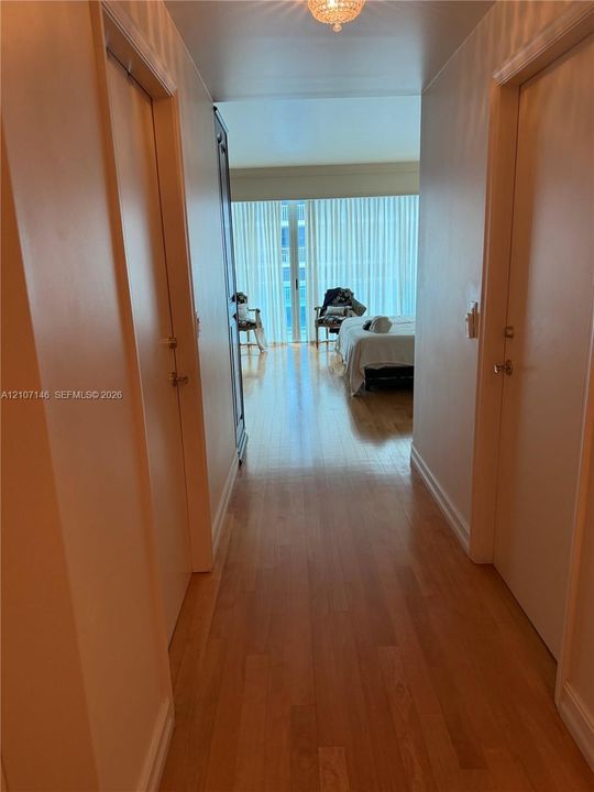 Hallway featuring wood-finish flooring, ceiling-mounted light fixture, and floor-to-ceiling window treatments