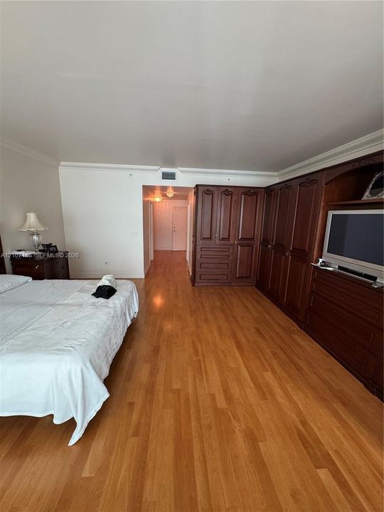 Wood-finish flooring, extensive built-in dark wood cabinetry, crown molding, and recessed ceiling lighting