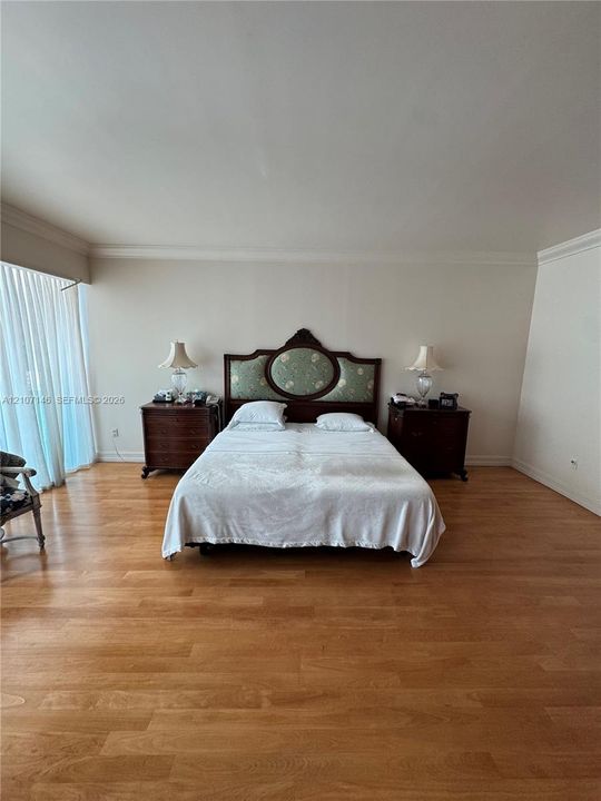 Room featuring wood-finish flooring, crown molding, and floor-to-ceiling drapery