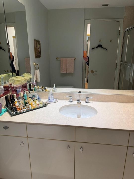 Bathroom vanity featuring a light-toned countertop, integrated oval basin, polished chrome widespread faucet, and flat-panel cabinetry