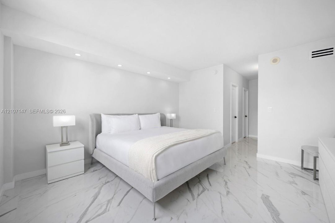 Neutral-toned interior featuring polished stone-finish flooring with veining, recessed cove lighting, and smooth-finish walls