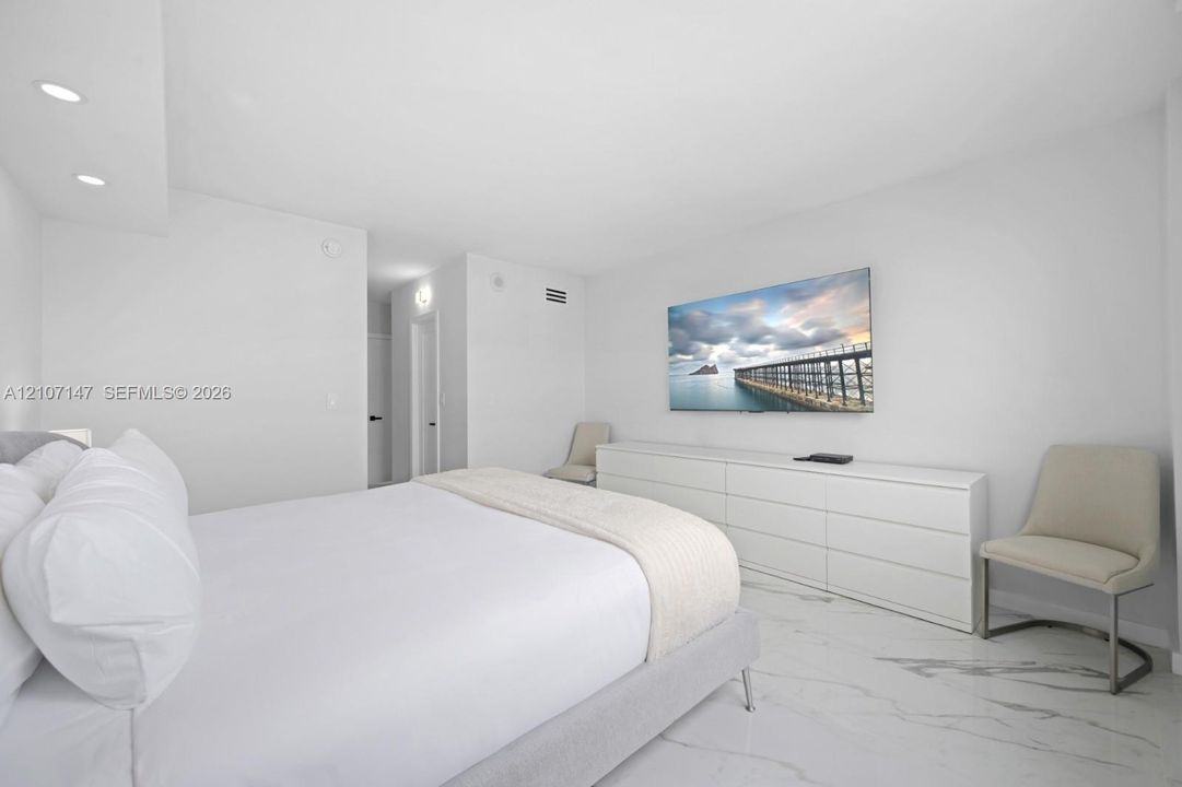 Neutral interior featuring large-format stone-patterned flooring, recessed ceiling lighting, and smooth finish walls