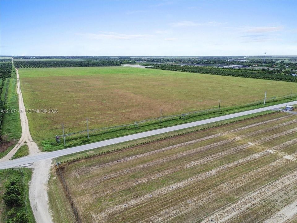 Expansive open acreage featuring extensive cleared land, direct paved road access, and perimeter agricultural bordering