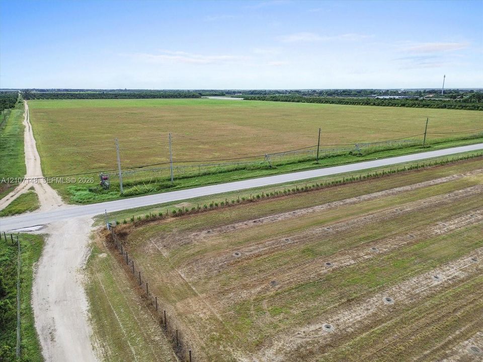 Expansive acreage featuring cleared land, paved road frontage, and perimeter fencing