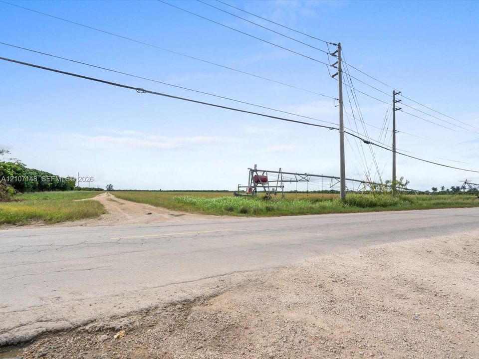 Expansive agricultural acreage featuring a center-pivot irrigation system and direct paved road frontage