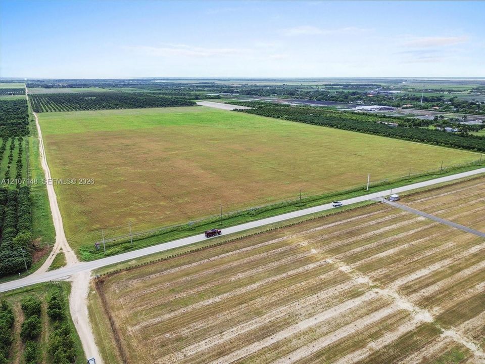 Expansive acreage featuring cleared land, established perimeter vegetation, and direct frontage on a paved thoroughfare