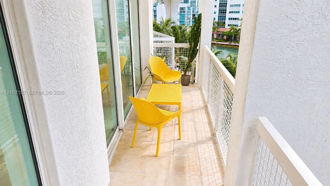 Covered balcony featuring tile flooring, textured stucco walls, and a white metal lattice railing