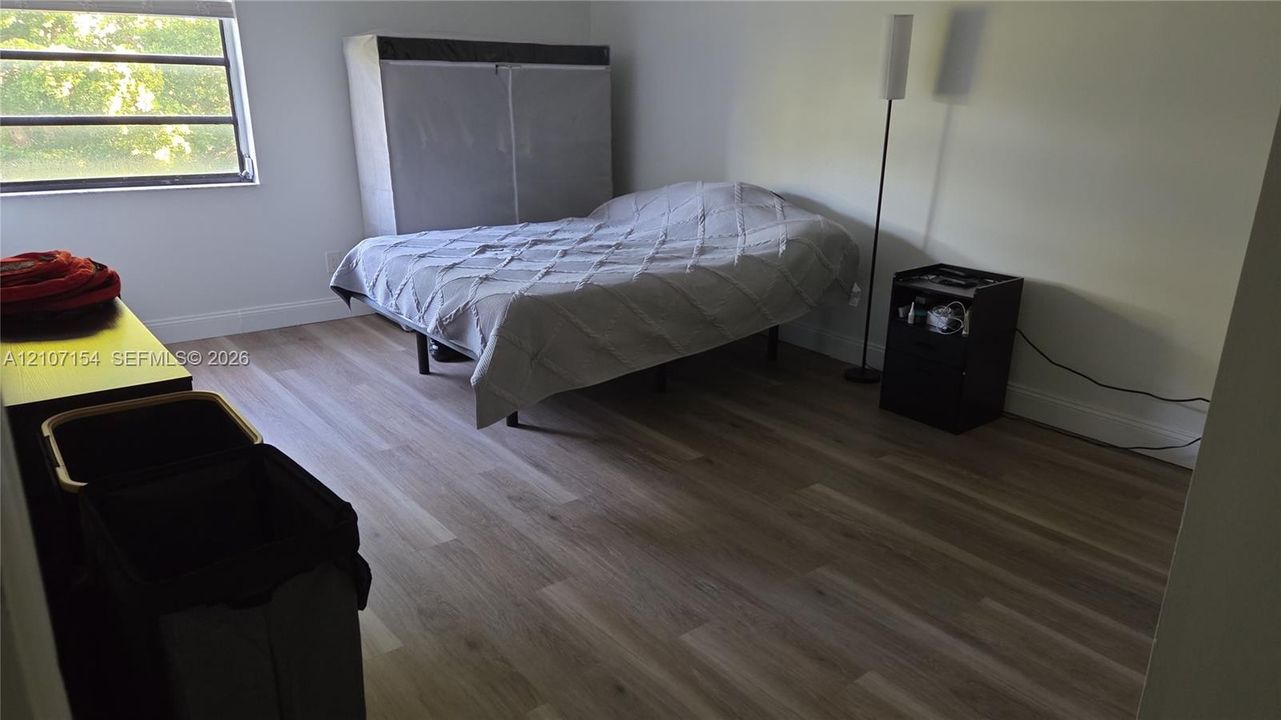 Neutral-toned room featuring wood-finish flooring and a window with a horizontal blind