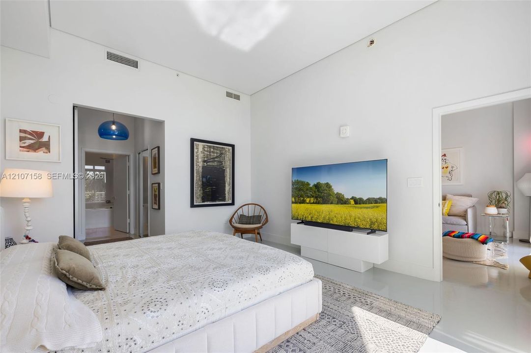 High-ceiling interior space featuring smooth-finish flooring and a white built-in media console