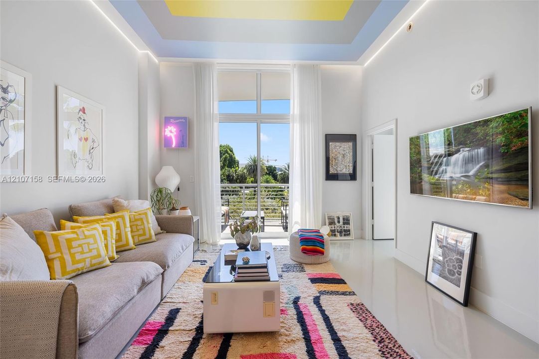 Multi-level tray ceiling with recessed perimeter lighting, floor-to-ceiling windows, polished flooring, and a private balcony with horizontal metal railing