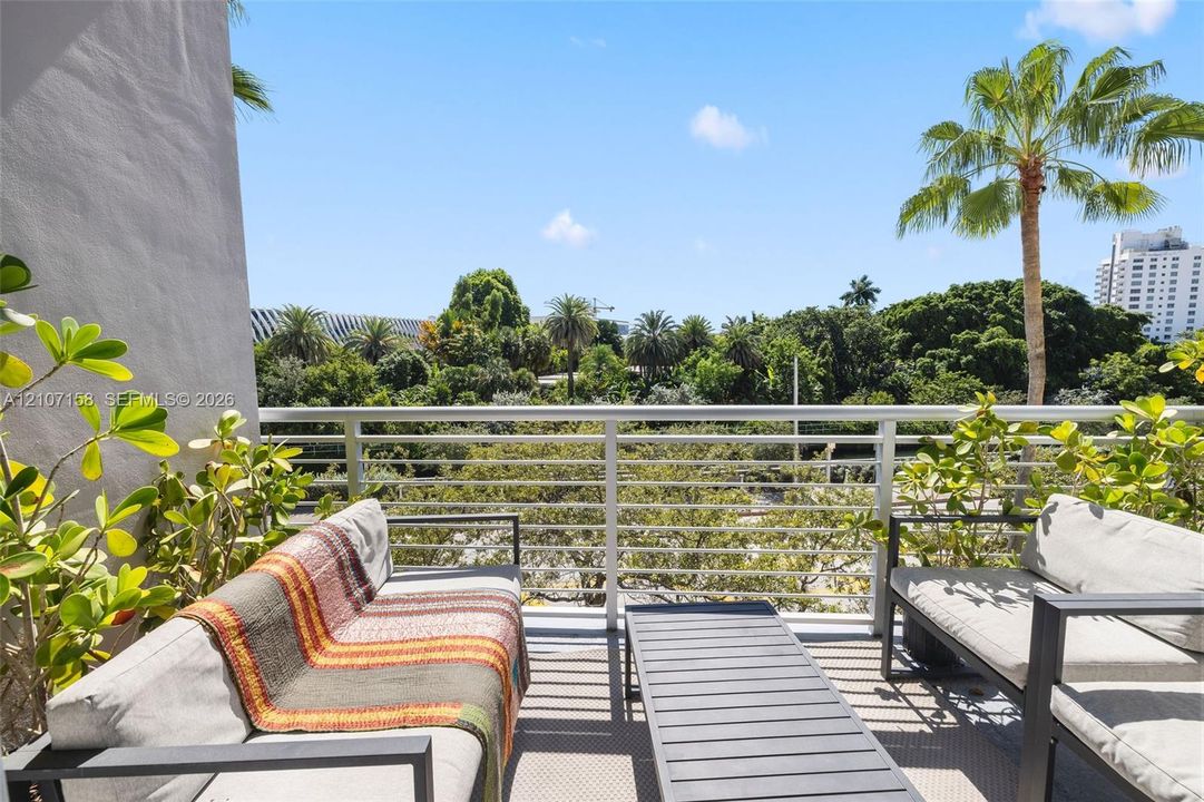 Private balcony featuring horizontal metal railing and mature tropical greenery