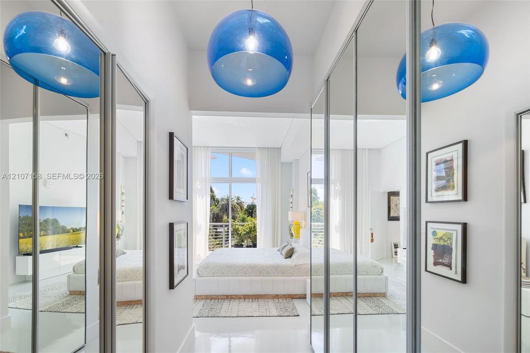 Full-height mirrored sliding wardrobe doors, polished flooring, and prominent spherical pendant lighting