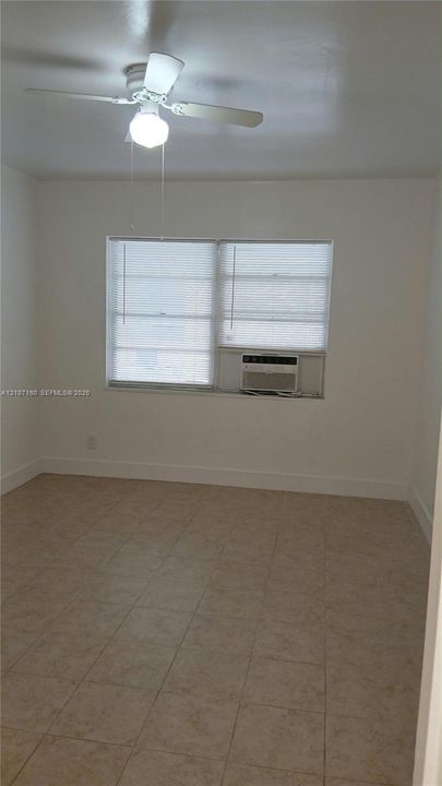Neutral-toned ceramic tile flooring, multi-pane window, and white ceiling fan with integrated lighting