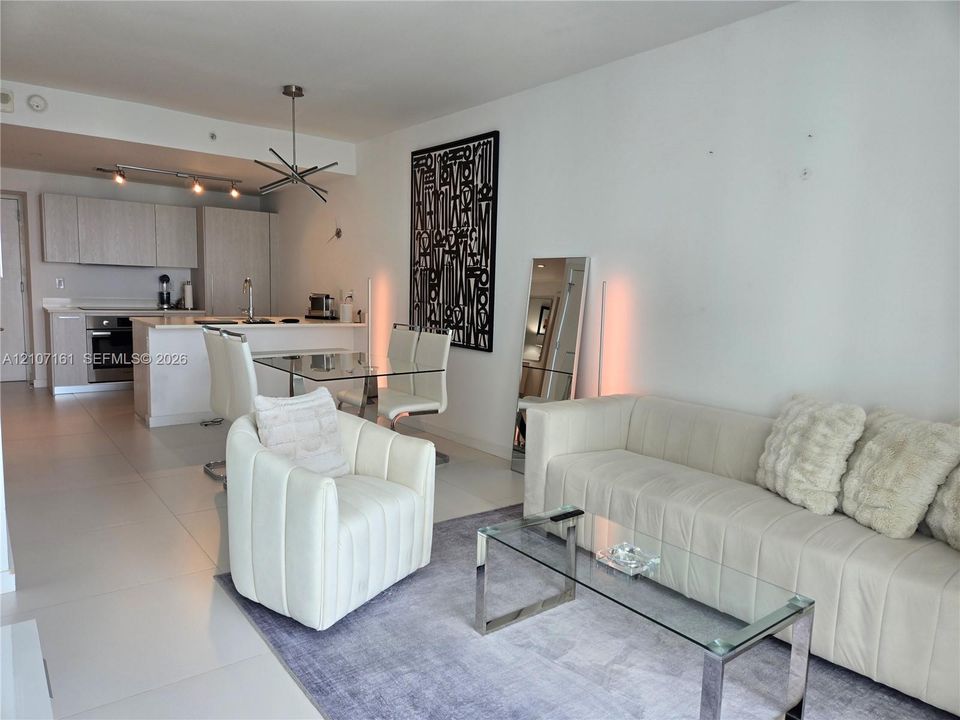 Open-concept interior featuring large-format tile flooring, flat-panel cabinetry, quartz countertops, and a modern multi-arm pendant light fixture