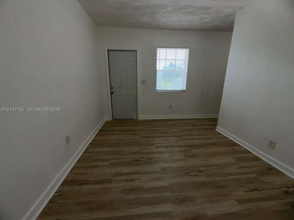 Interior space featuring wood-finish flooring, a multi-pane window, and a six-panel door